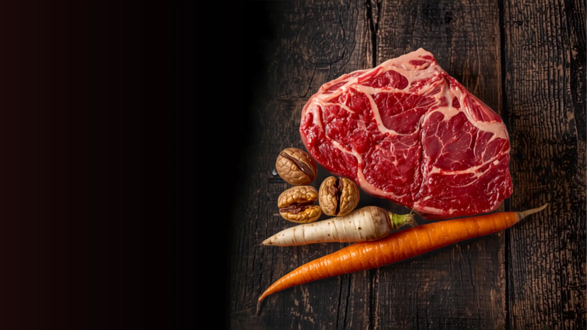 Paleo-ruokavalion raaka-aineita tummalla puupinnalla: raaka naudan pihvi, saksanpähkinöitä, palsternakka ja porkkana.